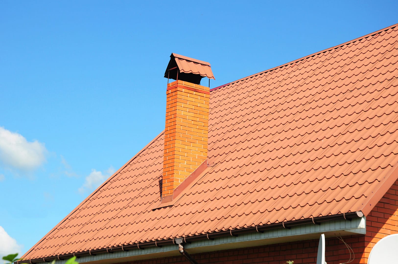 Old faded red metal roof tile and chimney.