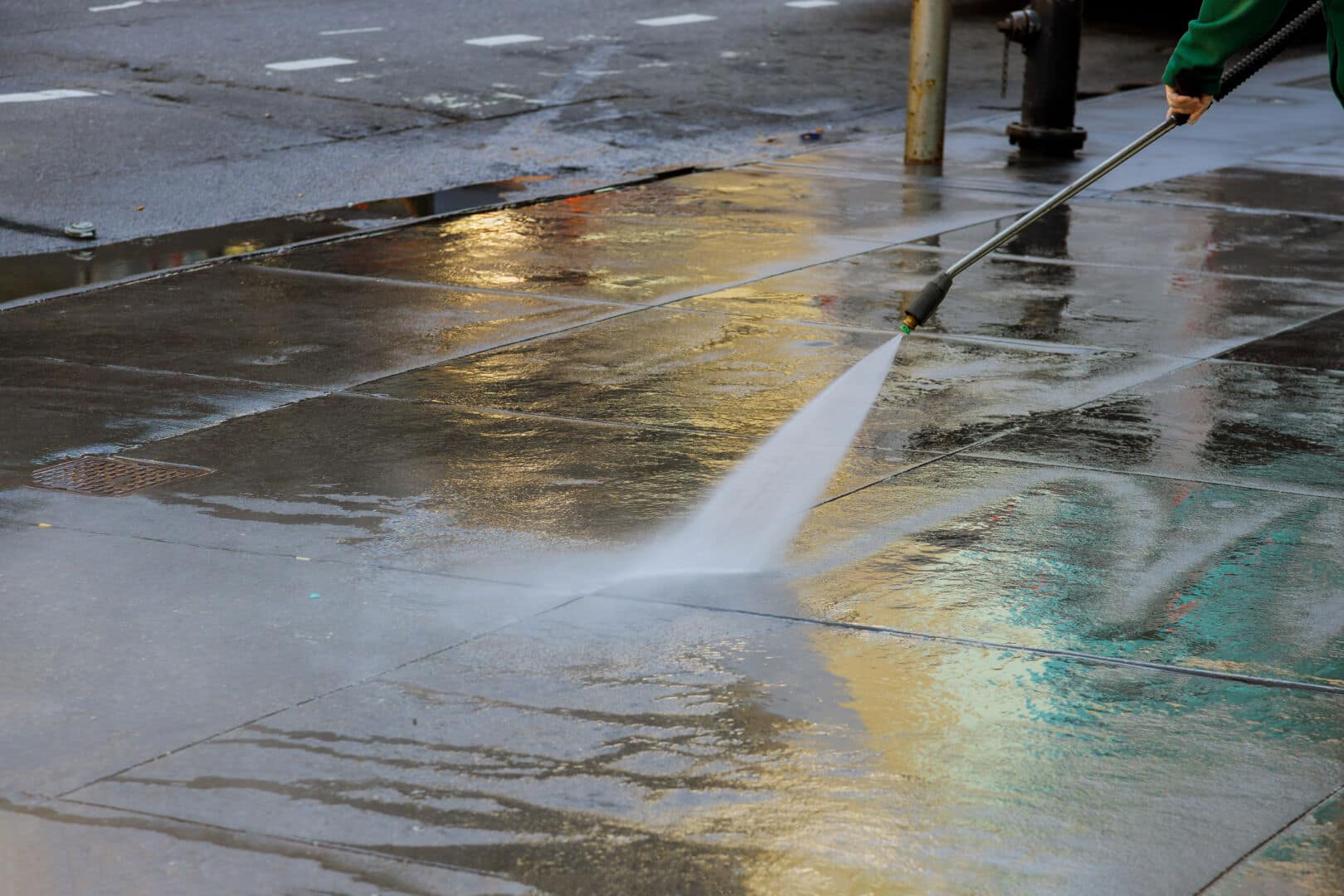 High pressure cleaning driveway with water washer splashing the asphalt road 5 Ways to Keep Your Patio Looking Like New! - pressure washer