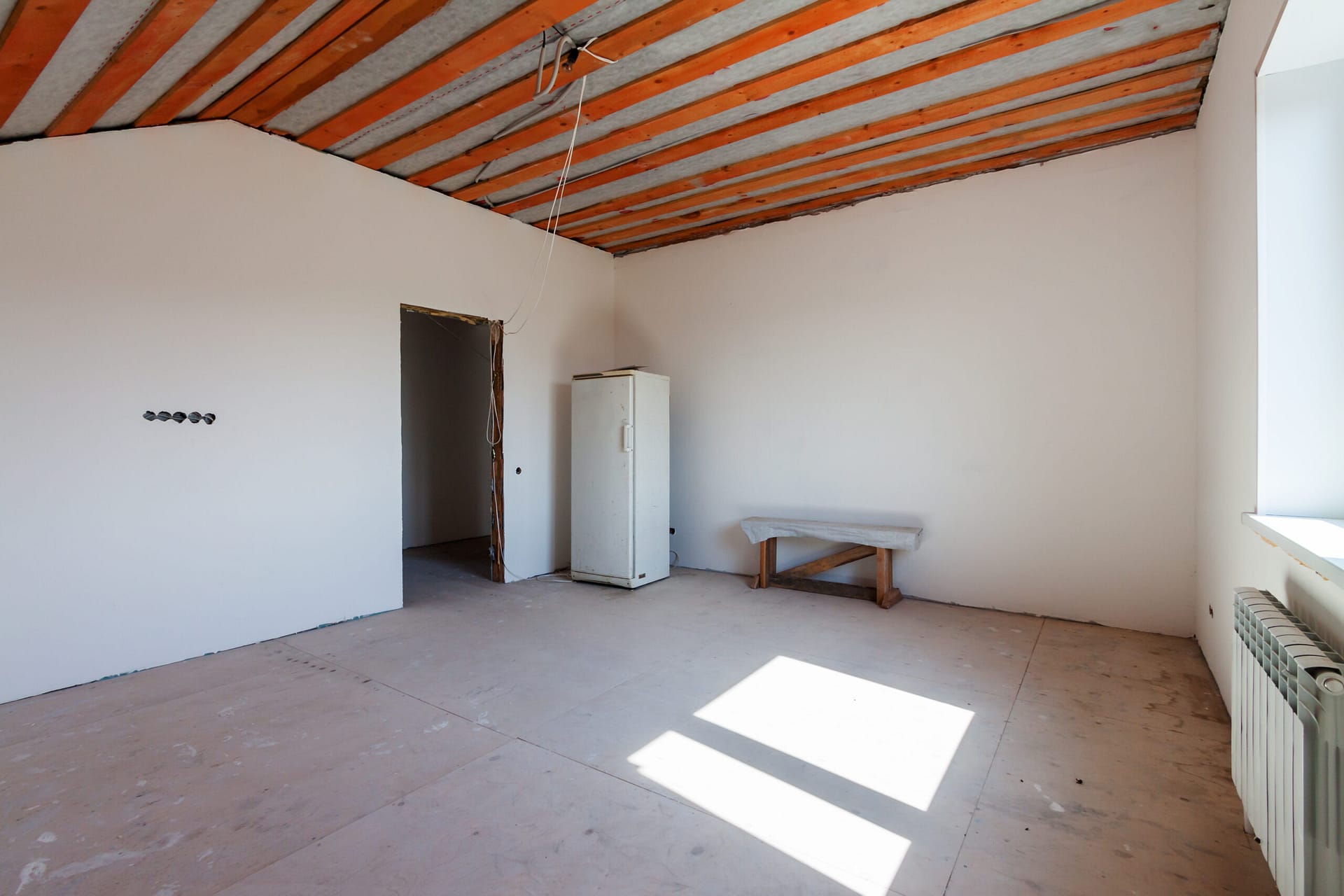 Renovation of residential building interior in progress to new white room single-family house with wooden ceiling roof beams.
