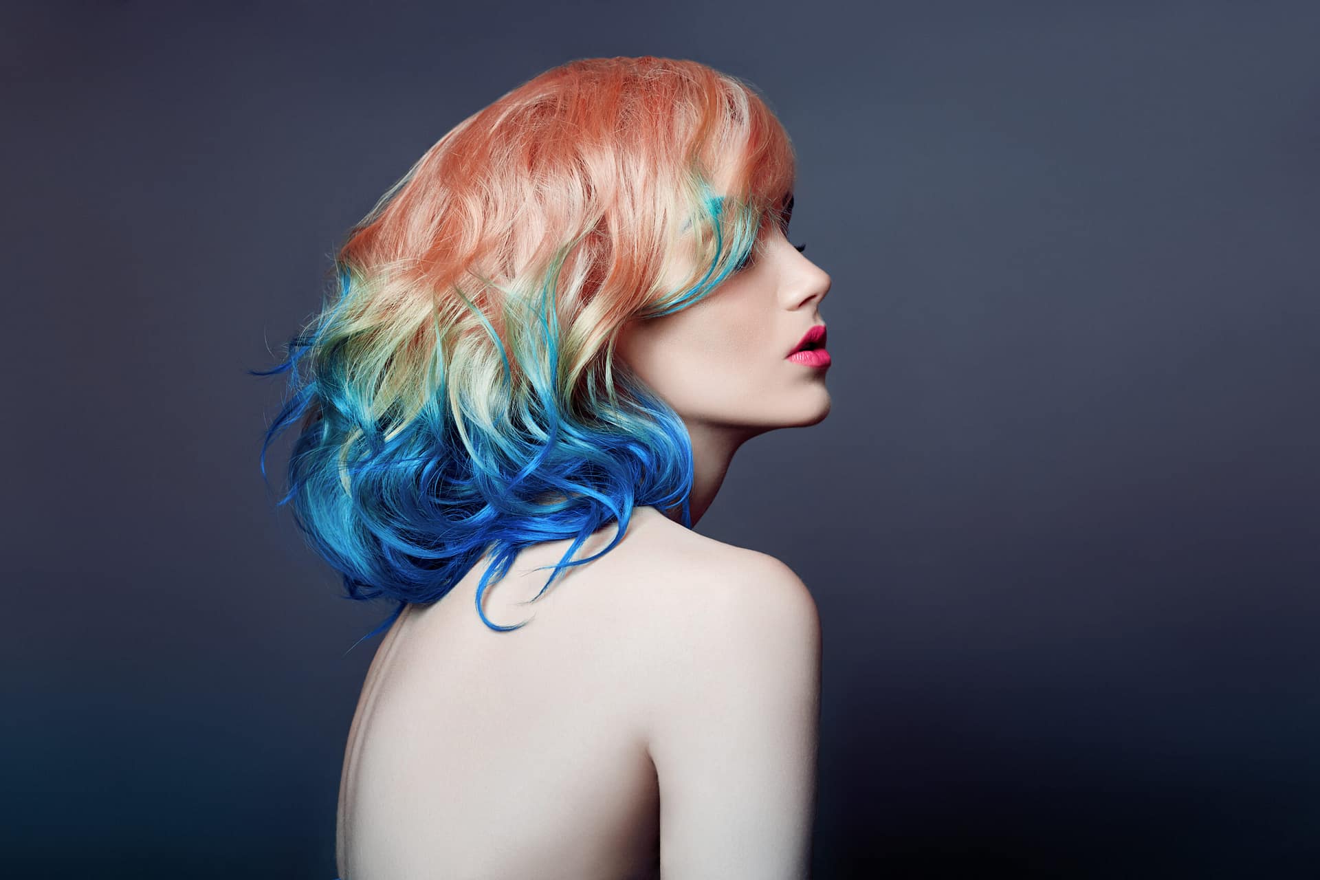 Portrait woman with bright colored flying hair, all shades purple blue. Hair coloring, beautiful lips and makeup. Hair fluttering in wind. Sexy girl with short hair. Professional creative coloring