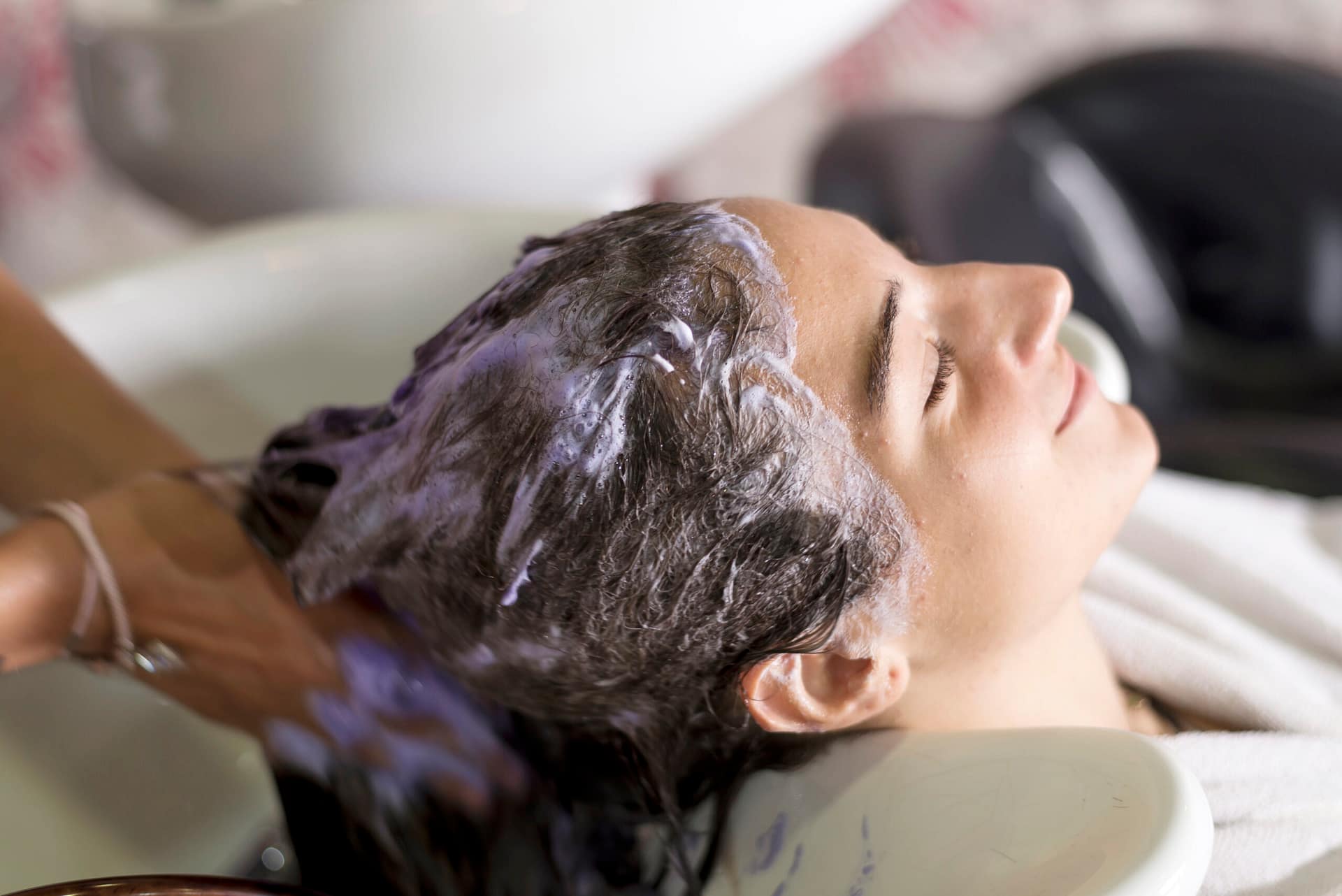 Young woman washing hair in salon